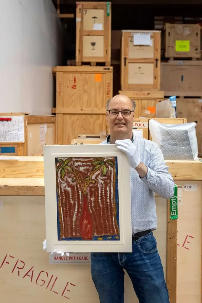 Arnold Ligthart met een schilderij uit zijn collectie